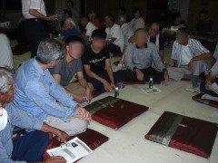 座布団の置かれた畳の上で複数のベトナム人実習生と地域住民が会話をしている写真