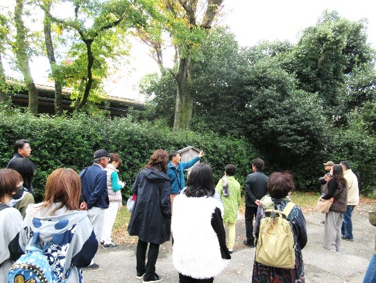 京都御苑周辺で立ち止まって講師の話を聞く参加者の姿