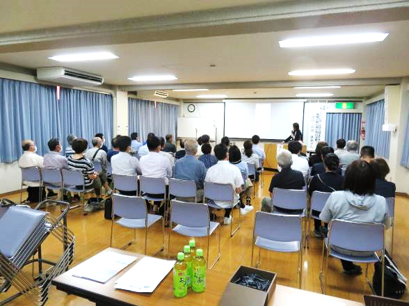 椅子に座って、講師の話を聞いている大勢の参加者の様子
