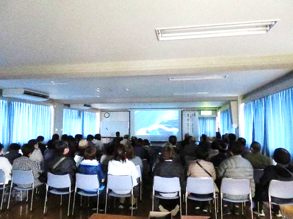 会議室で人権映画を見る、大勢の参加者の様子。
