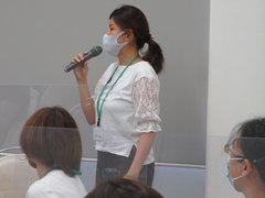 マイクを持ち自分の意見を発表する女性の写真
