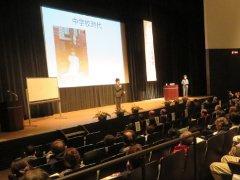 自分の中学校時代を映したスクリーンの前で講演を行う清水展人さんの写真