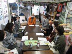 ひとつに繋げたテーブルに正座して集まり中心に座る井上一休さんの話を聞く参加者たちの写真