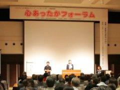 ステージ上で人権作文の発表をする女子中学生と隣で手話をする女性の写真