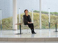 椅子に腰かけ講演を行うスーツ姿の女性の写真