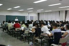 黒板の前に立ち講義を行う福田和博さんの話を机に座り資料を広げながら熱心に聞く保護者たちの写真