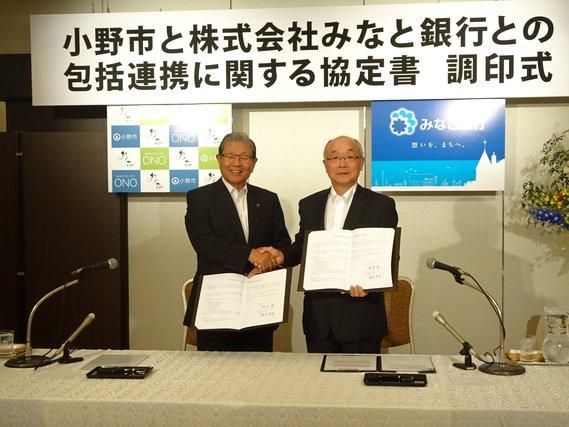 市長とみなと銀行の人が笑顔で握手している写真
