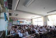 教室にいる生徒全員が手を挙げている写真