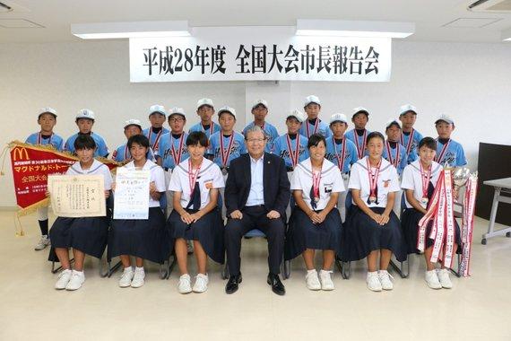 トロフィーや表彰状を持った全国大会に出場する学生たちと市長の記念写真