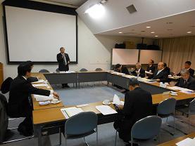 市長会議で大きなモニターの前で市長が発言している写真