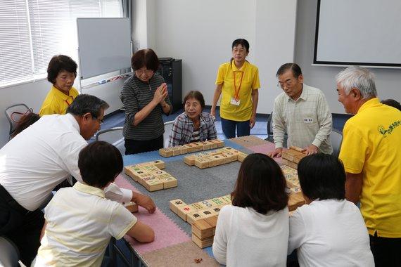 市長と黄色いシャツを着たスタッフが高齢者の方たちとコミュニケーション麻雀をしている写真