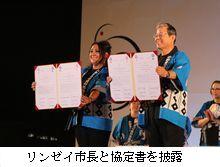 リンゼイ市長との協定書を披露している市長の写真