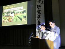 男性2人が大きなスクリーンを前に発表している小野市研究発表会の様子の写真