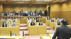 市長が前に立ち、1日議員となった女性議員たちと女性議会を開いている様子の写真