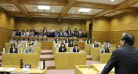 市長が前に立ち、1日議員となった女性議員たちと女性議会を開いている様子の写真