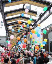 商店街の新アーケードのお披露目式で色とりどりのバルーンをリリースしている写真