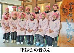 ピンクのエプロンと三角巾を身に着けた味彩会の13人の女性の集合写真