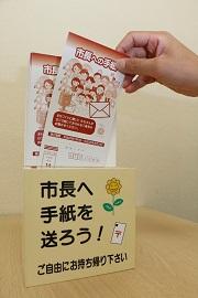「ご自由にお持ち帰り下さい」と書かれているボックスから市長への手紙を取り出している写真