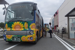 青地にひまわりがデザインされたらんらんバスに人々が乗り込もうとしている写真