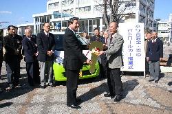 寄付された安全安心パトロールカーの前で小野ライオンズクラブの人と市長が握手をしている写真