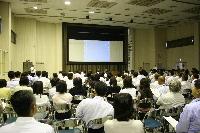 大きなスクリーンに映っているパワーポイントを沢山の人が見ている小野市職員研究発表会の写真