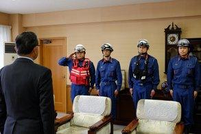 4人の消防隊員のうちの1人が市長に向かって敬礼している写真