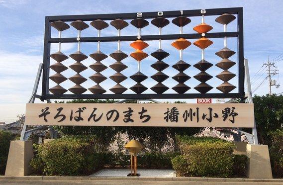 「そろばんのまち 播州小野」と書かれた看板の上にある巨大そろばんのモニュメントの写真