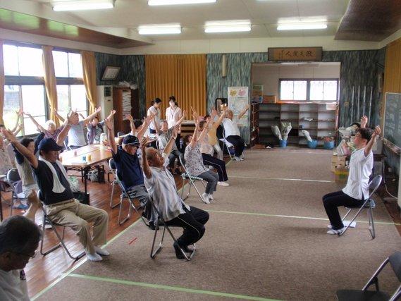 高齢者たちが椅子に座りながら体操をしているきずなづくりの写真