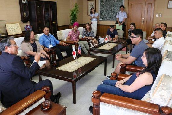 ソファに座りながらリンゼイ市親善訪問使節団と市長が笑顔で談笑している写真