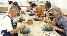 9人の人がエプロンを着て陶芸をつくっている写真