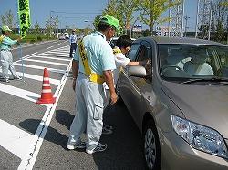 乗用車に手作りの交通安全啓発グッズを配布している交通安全運動の活動の様子の写真