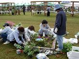 約1メートル四方のレンガの囲いにハーブを寄せ植えしている女性たちの写真