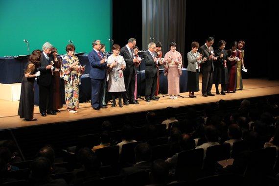 着物やスーツを着た高齢者の方たちがステージに立っているエイジ・ルネサンス・パーティの様子の写真
