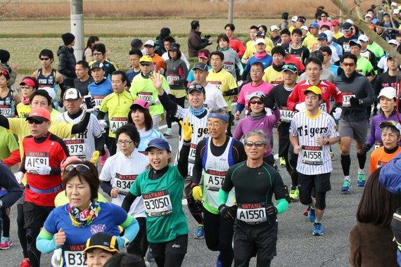 走りながらカメラに向かってピースをしている小野ハーフマラソンのランナーたちの写真