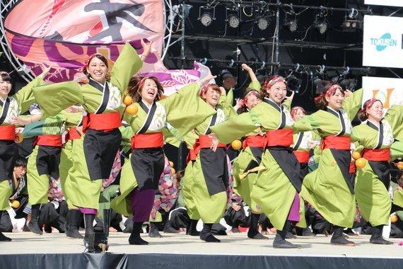 ステージの上で笑顔でおの恋おどりを踊っている人たちの写真