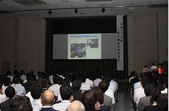 スクリーンにパワーポイントで作成をした資料を映しながら発表している職員研究発表会の写真