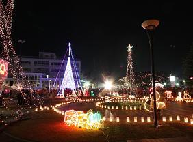 市役所前に飾られているクリスマスツリーや乗り物のオブジェなどのクリスマスイルミネーションの写真