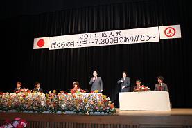 振袖やスーツを着た新成人達がステージの上に並び、発言している成人式の写真