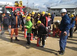小学生が消火器を使って消火訓練を行っている写真
