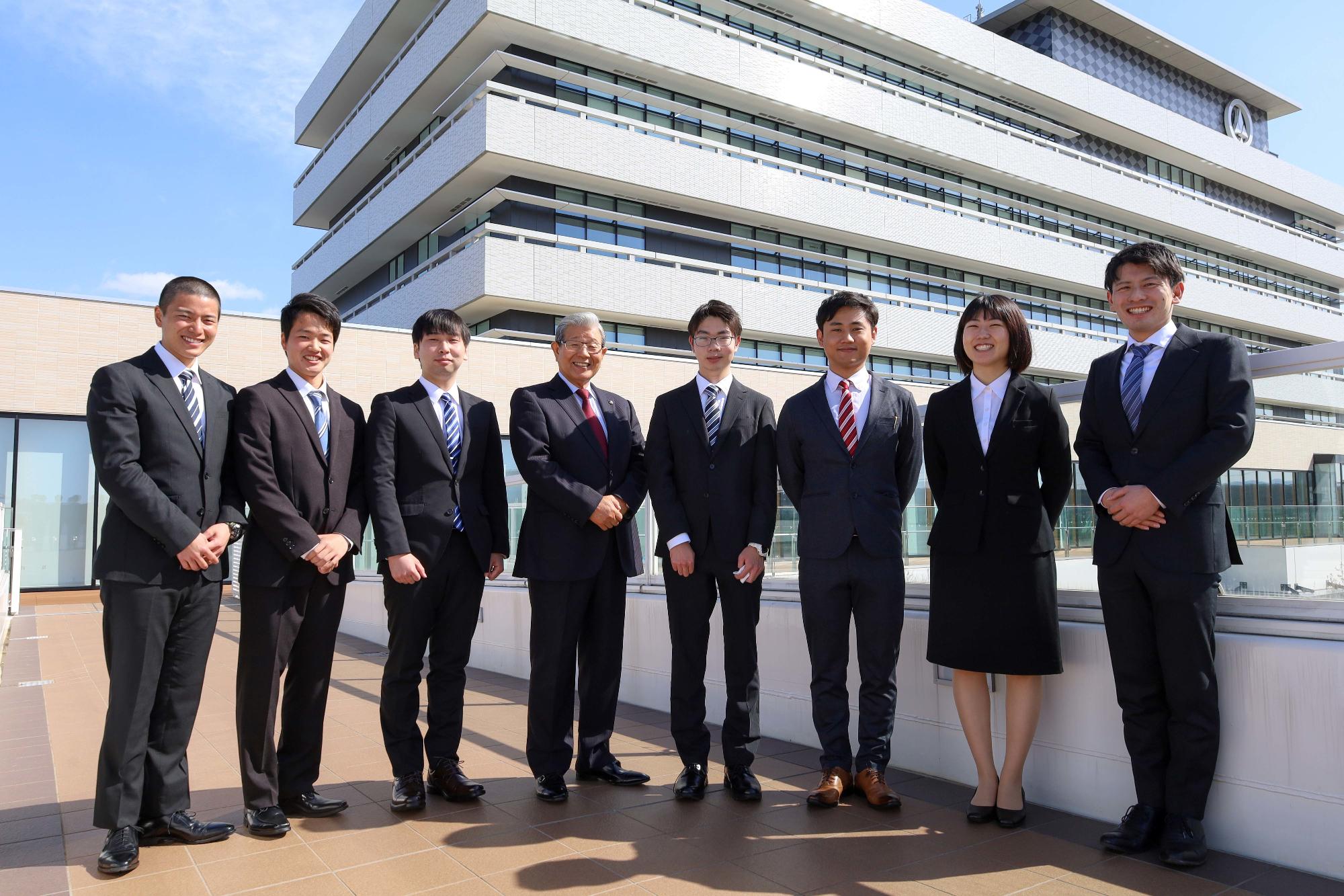 新庁舎を背に市長と集合写真を撮る新入社員の写真