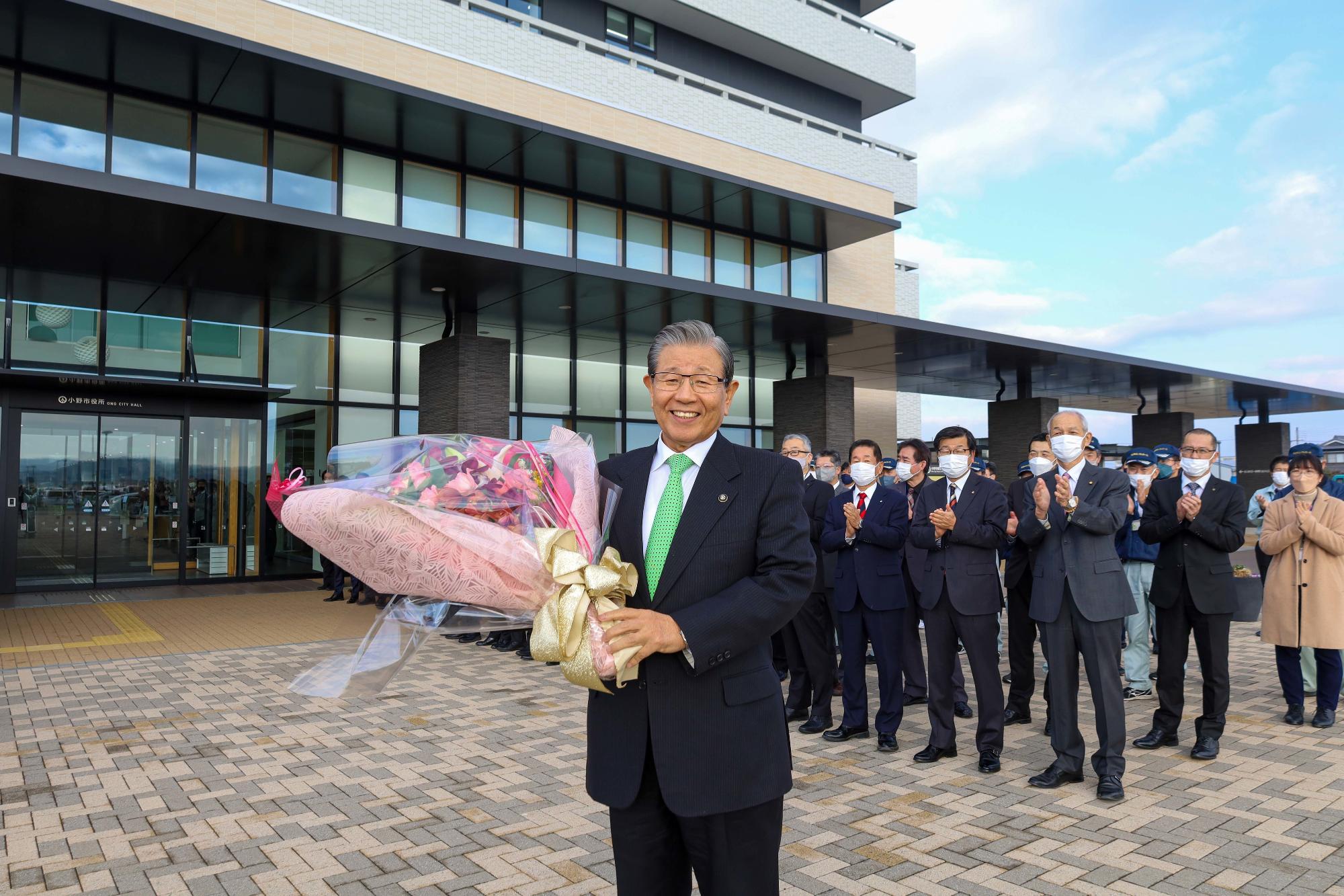 7期目の市長就任の初登庁に際し庁舎正面玄関で花束を掲げる市長の写真