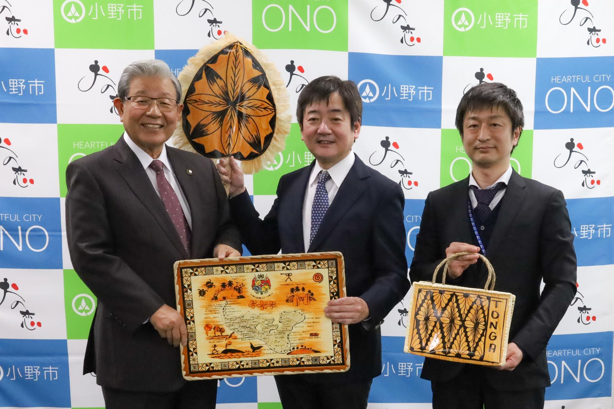 市長がトンガへのそろばん寄贈の返礼品をJICA職員から受け取っている場面の画像