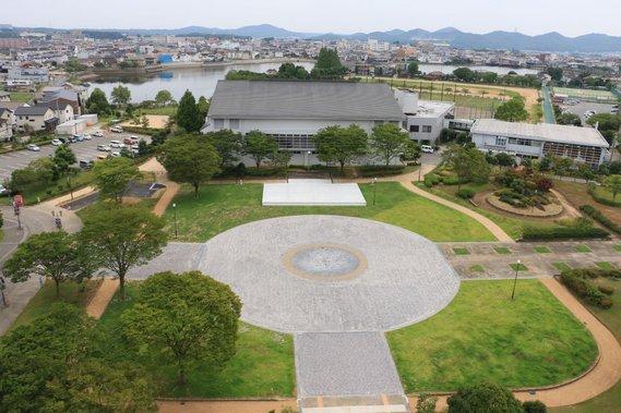 タイル張りの中央広場と、周りの芝生で構成された市民広場ステージ全体を上空から撮影した写真
