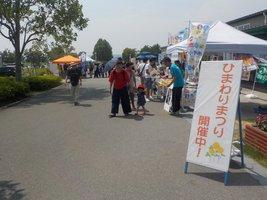 歩道沿いに三角テントが並ぶひまわりまつりの会場の様子の写真