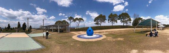 青い雫状の水飲み場を中心に公園を広く撮影したパノラマ写真