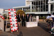 「成人式」の立て看板と共に外を出歩く晴れ着姿の新成人達の写真