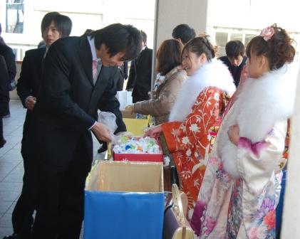 エコキャップを回収する実行委員と振り袖姿の新成人の列の写真