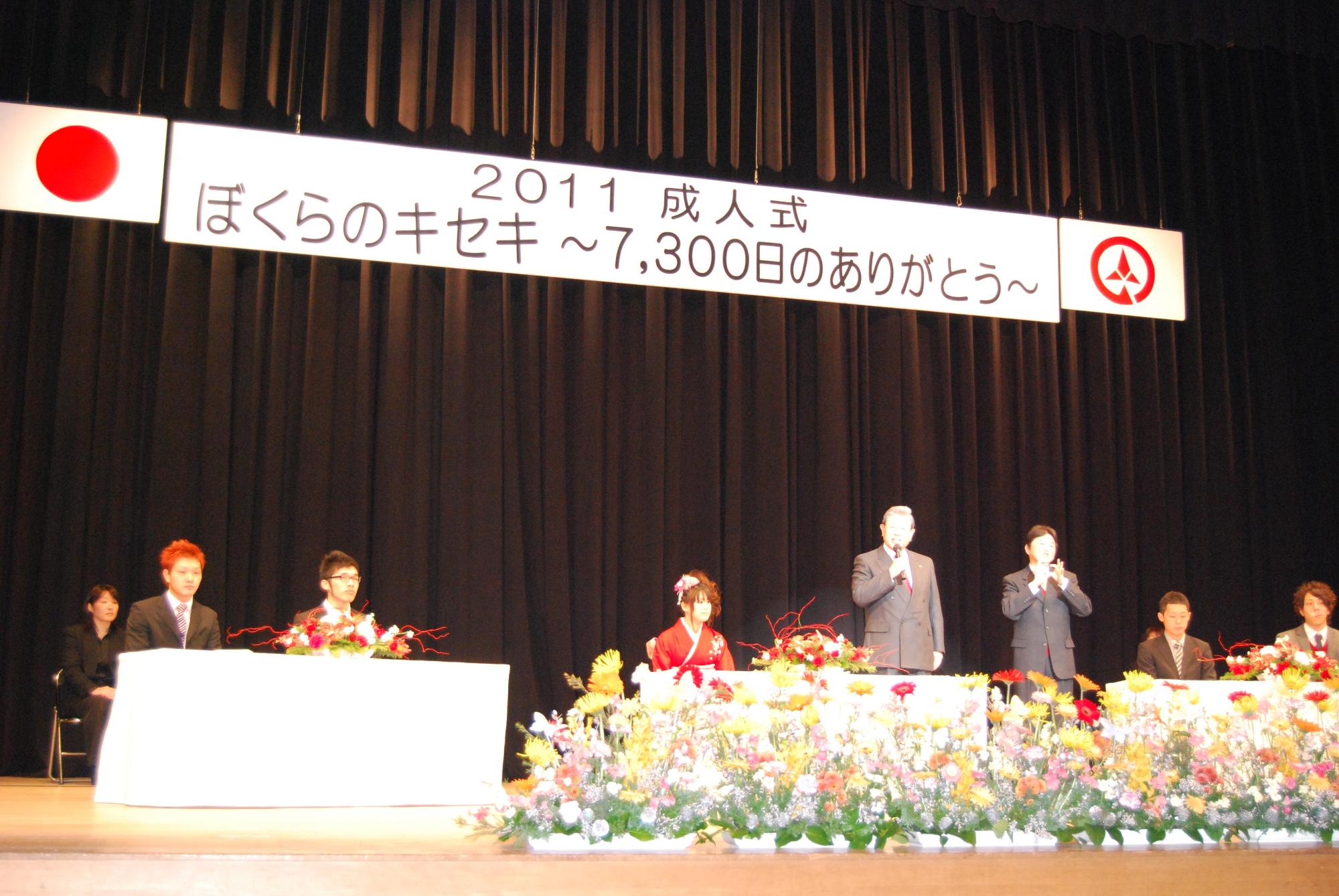 壇上でインタビュー&トークをする新成人と市長の頭上に、2011成人式ぼくらのキセキ~7300日のありがとう~の横断幕がある写真。
