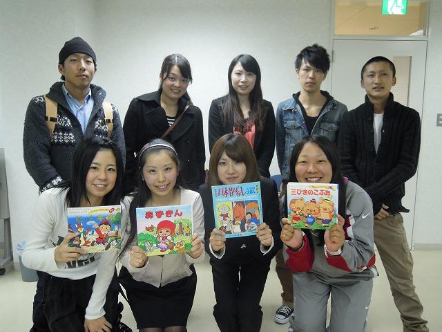 赤ずきんや日本昔ばなしなどの絵本を持って笑顔の実行委員会の方々の集合写真