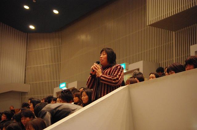 観客席から話す私服姿の女性の写真